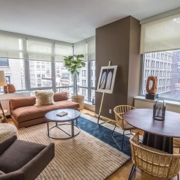 Spacious, upscale, and full of natural sunlight. Three-bedroom apartment homes leasing from $9,995. . . . #rosenyc #threebedroom #3bedroom #nyrealestate #nycrealestate #apartmentsforrent a living room with tables a couch and a rug